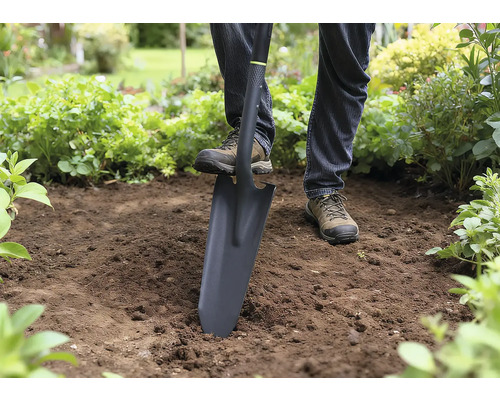 Une personne utilise une bêche pour creuser dans le jardin.