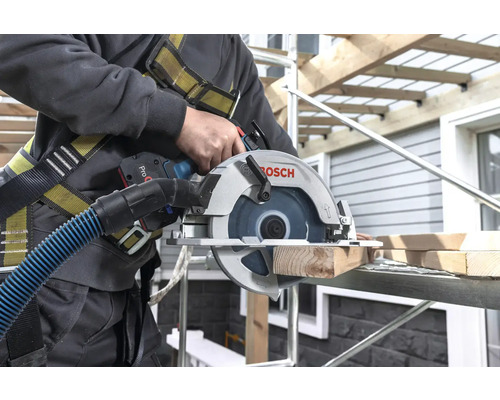 Artisan coupant du bois avec une scie circulaire Bosch sur un échafaudage.