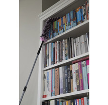 Un plumeau nettoie une bibliothèque avec des guides de voyage et des livres de cuisine