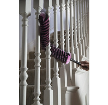 Une personne nettoie une rampe d'escalier blanche avec un plumeau.