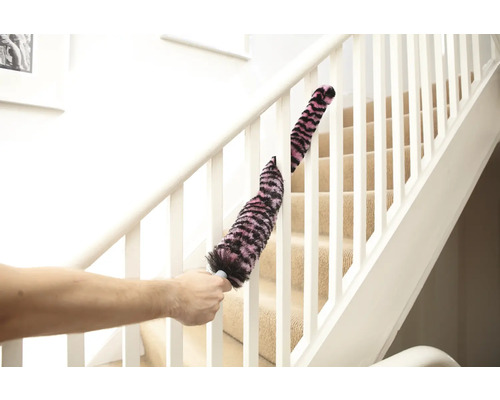 Une personne nettoie une rampe d'escalier avec un plumeau.