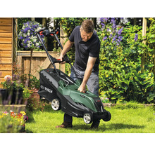 Ein Mann hebt einen Rasenmäher im Garten an