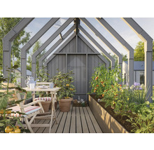 Serre avec table, chaises et plates-bandes surélevées plantées