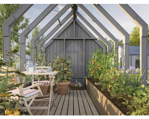 Serre avec table, chaises et plates-bandes surélevées plantées