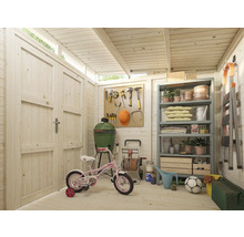 Intérieur d'abri de jardin avec étagères, outils, barbecue, vélo d'enfant et autres équipements de jardin.