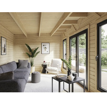 Intérieur lumineux d'une maison en bois avec des lambris, des meubles et de grandes fenêtres.