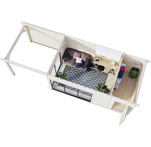 Vue intérieure d'une cabane de jardin avec canapé, bureau, tapis, étagères et outils de jardin.