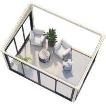 Salon de jardin lumineux avec parois en verre, fauteuils et plantes