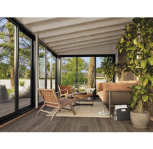 Véranda lumineuse avec coin salon, grande fenêtre et plancher en bois