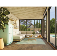 Salon lumineux avec canapé, table, réfrigérateur de la marque SMEG et vue à travers la façade vitrée sur le jardin avec piscine.