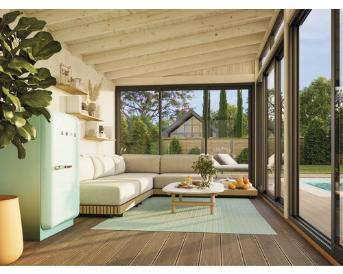 Salon lumineux avec canapé d'angle, table de cuisine, réfrigérateur SMEG et vue sur le jardin avec piscine