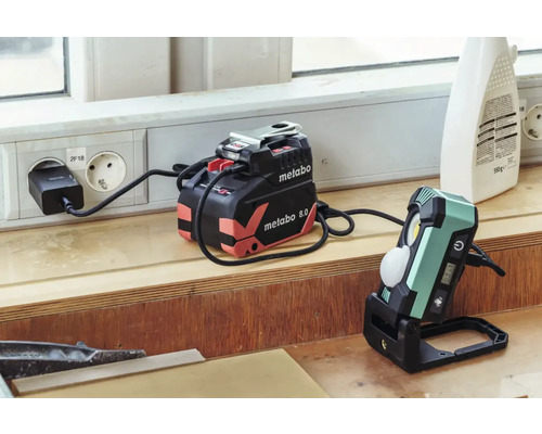 Chargeur de batterie Metabo et projecteur de chantier sans fil sur un établi
