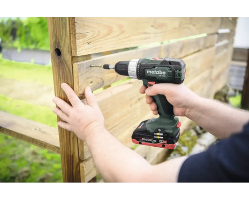 Une personne visse une palette en bois avec une visseuse sans fil de la marque Metabo.