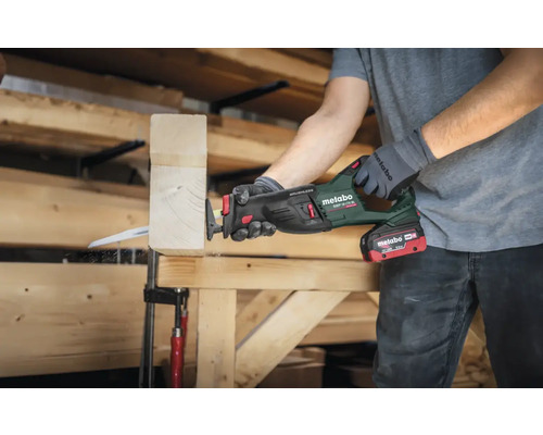 Une personne utilise une scie sabre sans fil Metabo pour couper un morceau de bois.