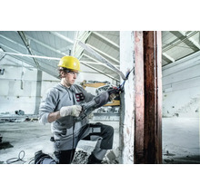 Un ouvrier du bâtiment utilise une scie sabre Metabo pour couper du métal sur un chantier.