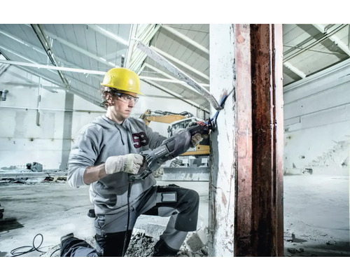 Un ouvrier du bâtiment utilise une scie sabre Metabo pour couper du métal sur un chantier.