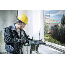 Un homme portant un casque et des lunettes de protection travaille sur un cadre de fenêtre avec une scie sabre Metabo.