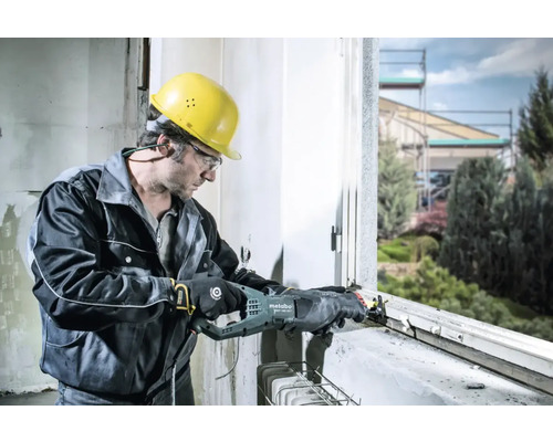 Un homme portant un casque et des lunettes de protection travaille sur un cadre de fenêtre avec une scie sabre Metabo.