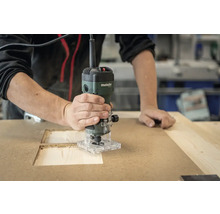 Une personne fraise une cavité dans une plaque de bois à l'aide d'une défonceuse.