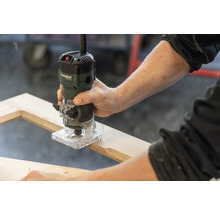 Une personne utilise une défonceuse Metabo sur un cadre en bois.