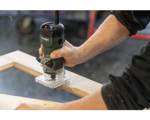 Une personne utilise une défonceuse Metabo sur un cadre en bois.