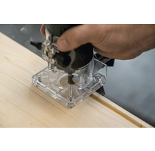 Défonceuse à main en train de fraiser une rainure dans une planche de bois.