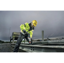 Un ouvrier du bâtiment avec un casque de protection perce une pièce métallique avec une perceuse.