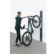 Une femme accroche un VTT électrique à un support mural.