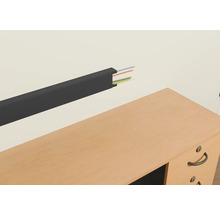 Kabelkanal aus Kunststoff mit Kabeln an einer Wand über einem Schreibtisch