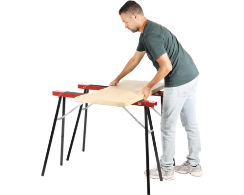 Un homme pose une planche en bois sur deux tréteaux