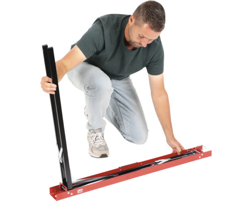 Un homme assemble un gabarit de coupe de carreaux en métal pour grands carreaux