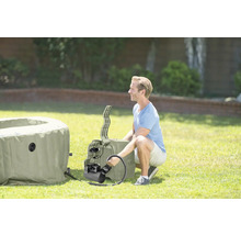 Un homme installe un jacuzzi gonflable dans le jardin.