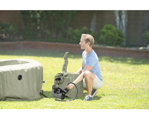 Un homme installe un jacuzzi gonflable dans le jardin.