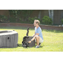 Un homme assemble un spa gonflable dans le jardin.