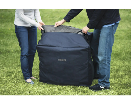 Des personnes transportent une housse de protection de la marque Intex sur une pelouse