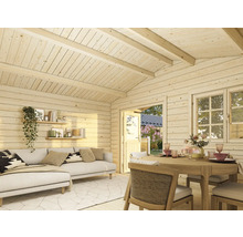 Pièce en bois clair avec canapé, étagères, table à manger et fenêtres pour une ambiance chaleureuse.