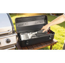 Set d'ustensiles de barbecue dans une boîte de rangement noire à côté d'un barbecue