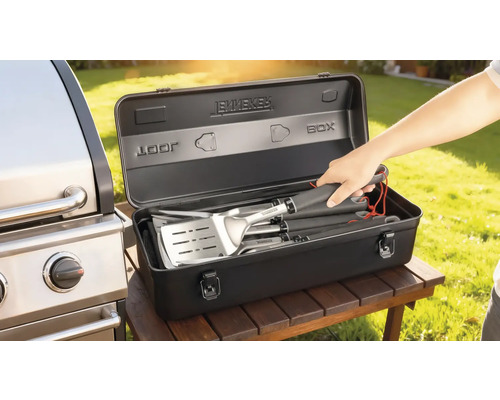 Set d'ustensiles de barbecue dans une boîte de rangement noire à côté d'un barbecue