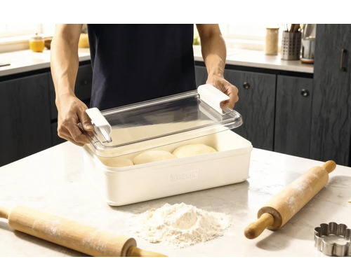Boîte à pâte avec couvercle et deux rouleaux à pâtisserie ainsi que de la farine sur un plan de travail de cuisine