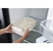 Une personne place un saladier à pâte avec couvercle dans le réfrigérateur