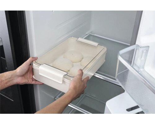 Une personne place un saladier à pâte avec couvercle dans le réfrigérateur