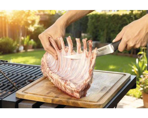 Préparation de carré d'agneau sur une planche à découper en bois avec un couteau Tenneker dans le jardin.