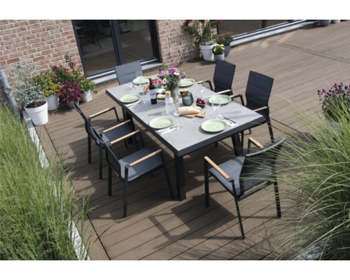 Ein Esstisch mit Stühlen auf einer Terrasse, gedeckt mit Tellern und Besteck.