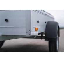 Detailansicht eines Pkw-Anhängers mit weißem Frontreflektor, gelbem Seitenreflektor und schwarzem Kunststoffkotflügel.