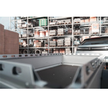 Leerer Anhänger angekoppelt an ein Auto in einem organisierten Drive In Baumarkt vor Regalen mit Baumaterialien.