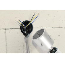 Mur avec trou de forage, câbles électriques et une scie cloche.