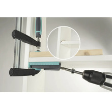 Une perceuse perce un trou dans une étagère à l'aide d'un gabarit de perçage.