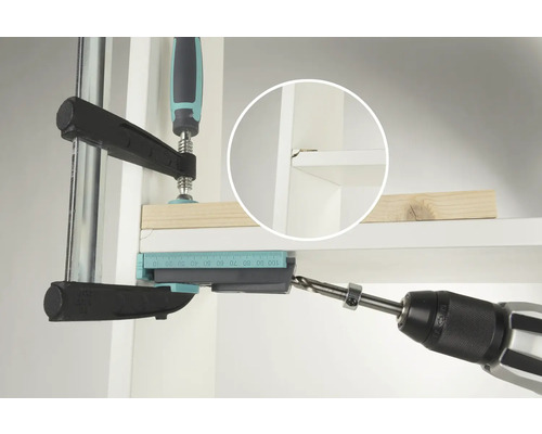 Une perceuse perce un trou dans une étagère à l'aide d'un gabarit de perçage.