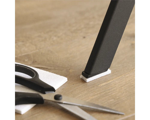 Pied de chaise avec patin en feutre, patin en feutre et ciseaux sur plancher en bois