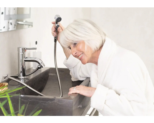 Femme dans la salle de bain avec douchette de bidet sur le lavabo